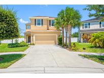 Two-story house with tan exterior, two-car garage, and landscaped yard at 8315 Round Leaf Ln, Riverview, FL 33578