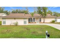 Single-story house with brown roof, light walls, and a well-maintained lawn at 23315 Charlston Pl, Land O Lakes, FL 34639