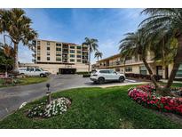 Exterior of a condominium building with lush landscaping, parking, and a beautiful, sunny day at 6180 Sun Blvd # 302, St Petersburg, FL 33715