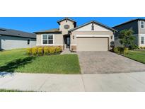 One-story house with tan siding, stone accents, and a two-car garage at 7122 Heron Walk Ln, Wesley Chapel, FL 33545