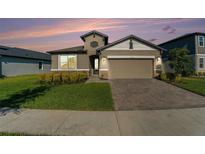 Two-story house with tan siding, stone accents, and a two-car garage at 7122 Heron Walk Ln, Wesley Chapel, FL 33545