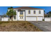 Two-story home with white exterior, three-car garage, arched windows, and front yard at 11309 Outrigger Ave, Spring Hill, FL 34608