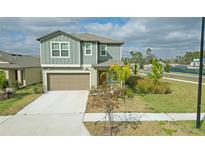 Two-story house with green siding, brown garage door, and landscaping at 22547 Storybook Cabin Way, Land O Lakes, FL 34637
