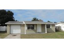 Tan single-story house with attached garage and well-maintained lawn at 9315 Gray Fox Ln, Port Richey, FL 34668