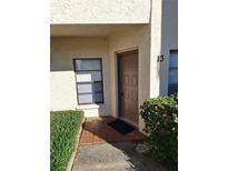 Condo building entry with brown door, tile entryway and landscaping at 3536 Countrybrook Ln # 13, Palm Harbor, FL 34684