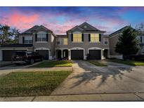 Evening view of three-story townhouses with attached garages at 6912 Rock Springs Way, Tampa, FL 33625