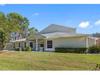 Spacious single-Gathering home with well-manicured lawn, mature trees, and a light-colored facade on a bright day at 3203 Audubon Ct, Tarpon Springs, FL 34688