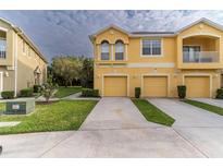 Front view of a two-story townhome with a two-car garage and landscaped lawn at 9042 Moonlit Meadows Loop, Riverview, FL 33578
