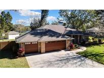 Brick house with a two-car garage and landscaped yard at 19505 Coachlight Way, Lutz, FL 33549