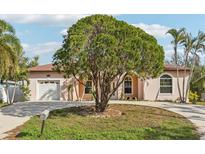 Attractive light pink house with circular driveway, lush landscaping, and a two-car garage at 5269 61St N Way, Kenneth City, FL 33709