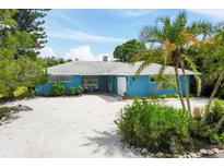 Charming mid-century home with a light blue exterior, white trim, and a gravel driveway at 616 Lyons Ln, Longboat Key, FL 34228