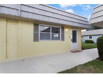 Exterior view of a yellow building with a gray roof and white door at 201 Bedford St # 79, Sun City Center, FL 33573