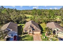 Charming single-Gathering home boasts a manicured lawn and paver driveway in a serene, tree-lined neighborhood with golf course views at 4275 Caskie Pl, Brooksville, FL 34604