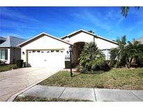 Charming single-story home featuring a two-car garage, manicured lawn, and lush tropical landscaping at 11021 Edge Park Dr, Hudson, FL 34667