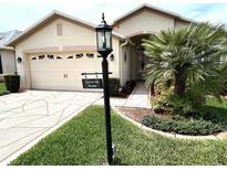 Charming single-story home featuring a two-car garage, manicured lawn, and tropical landscaping at 11021 Edge Park Dr, Hudson, FL 34667