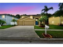 Charming two-story home with a well-manicured lawn, palm trees, and a three-car garage at 15815 Muirfield Dr, Odessa, FL 33556