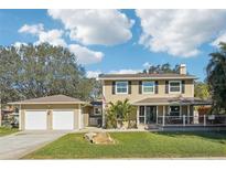 Charming two-story home with a well-manicured lawn, detached garage, and inviting front porch at 13945 75Th Ave, Seminole, FL 33776