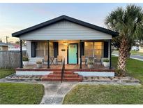 Charming bungalow with a welcoming porch, vibrant blue door, and well-manicured landscaping at 2701 W Cordelia St, Tampa, FL 33607