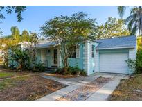 Charming blue single-story home features a garage and a brick-lined driveway, enhancing its curb appeal at 2932 W Alline Ave, Tampa, FL 33611