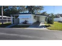 Charming home exterior with a carport, manicured lawn, and mature trees in the community at 27466 Us Highway 19 N # 97, Clearwater, FL 33761