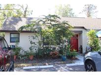 Inviting single-story home featuring a bright red front door, complemented by lush greenery and convenient parking at 2912 Star Apple Ct, Palm Harbor, FL 34684