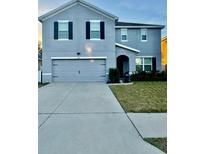 Charming two-story home with a gray facade, well-maintained lawn, and a two-car garage at 451 Hartford Heights St, Spring Hill, FL 34609