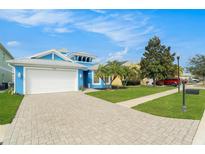 Charming blue exterior with well-manicured lawn, complemented by a paved driveway leading to a two-car garage at 6408 Key Island Ave, Apollo Beach, FL 33572