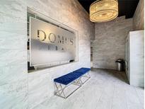 Elegant lobby with Domus Urbana sign, modern chandelier, blue bench seating, and marble wall at 644 3Rd S Ave # 302, St Petersburg, FL 33701