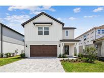 Charming two-story home featuring a brick driveway, attached garage, and manicured landscaping at 6690 Michael Favor Way, Wesley Chapel, FL 33545