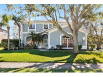 Inviting two-story home featuring a well-manicured lawn, lush tropical landscaping, and a charming entryway at 1600 Gray Bark Dr, Oldsmar, FL 34677