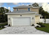 Two-story home featuring a gray roof, attached garage, and gray paver driveway at 11594 Oak Ln, Largo, FL 33778