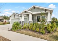 Charming two-car garage home with stone accents, covered porch, and beautifully landscaped front yard at 6189 Hidden Branch Dr, Apollo Beach, FL 33572
