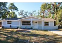 Charming single-story home featuring a well-maintained front yard with mature trees and a freshly painted exterior at 7160 Lenape Cir, New Port Richey, FL 34653