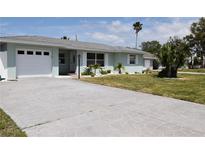 Beautiful one-story home featuring a large driveway, attached garage, well-manicured lawn and updated windows at 123 9Th St, Belleair Beach, FL 33786