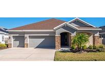 Charming single-story home featuring a two-car garage, stone accents, and a well-maintained lawn at 17671 Bright Wheat Dr, Lithia, FL 33547