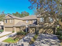 Two-story townhome featuring a neutral color scheme, attached garages, and manicured landscaping at 4207 Key Thatch Dr, Tampa, FL 33610