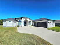 Stunning home featuring a manicured lawn, a wide driveway, and an attached three-car garage at 11199 Warm Wind Way, Weeki Wachee, FL 34613