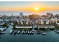 Stunning aerial view of waterfront condos with boat docks and a beautiful sunset over the ocean at 5301 Gulf Blvd # E202, St Pete Beach, FL 33706