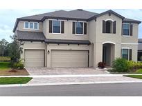Charming two-story home features a three-car garage and brick-paved driveway at 12854 Boggy Creek Dr, Riverview, FL 33579