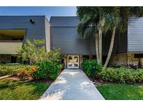 Modern condo building exterior featuring well-maintained landscaping and a welcoming entrance at 36750 Us Highway 19 # 21-301, Palm Harbor, FL 34684
