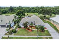 Beautiful one-story home with a manicured front lawn, lush landscaping, and a nearby golf course view at 394 Tall Oak Trl, Tarpon Springs, FL 34688