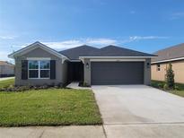 Charming single-story home with a gray exterior, well-manicured lawn, and a two-car garage at 13290 Ogden Glade Rd, Dade City, FL 33525