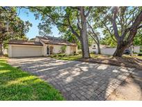 Inviting single-Gathering home featuring a two-car garage and a brick driveway, framed by mature trees at 4822 W San Miguel St, Tampa, FL 33629