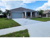 Charming single-story home featuring a brick facade, well-manicured lawn, and a two-car garage at 422 Shannon Estates Ct, Plant City, FL 33563