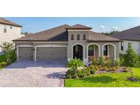 Charming single-story home with a brick driveway, neutral stucco, three-car garage and beautiful landscaping at 13028 Homestead Ln, Parrish, FL 34219