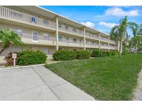 A three story condo building with white railings overlooks a green lawn with flowering bushes and palm trees at 3987 Maceachen Blvd # 133, Sarasota, FL 34233