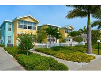Inviting two-story building with colorful exterior, white picket fence, and lush landscaping at 19417 Gulf Blvd # C210, Indian Shores, FL 33785