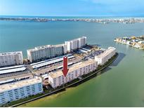 A captivating aerial view of a waterfront condominium complex surrounded by pristine turquoise waters at 6025 Shore S Blvd # 311, Gulfport, FL 33707