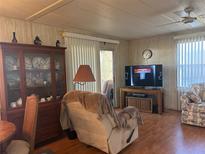 Inviting living room with wood floors, ceiling fan, and a large display cabinet at 12501 Ulmerton Rd # 140, Largo, FL 33774
