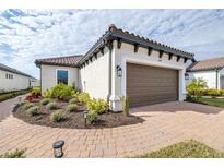 Home exterior featuring a tile roof, two-car garage, and paved driveway with well-maintained landscaping along the walkway at 4639 Garofalo Rd, Wesley Chapel, FL 33543